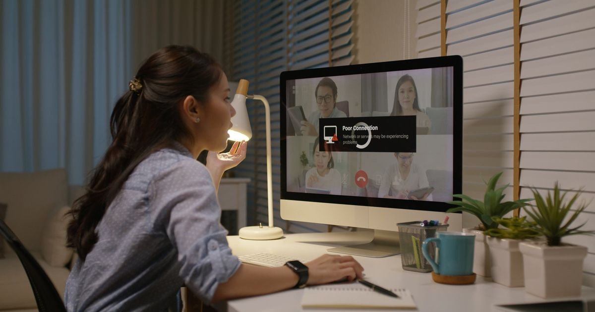 Eine junge Frau schaut empört auf Ihren Computer-Bildschirm. Darauf sind eine Videokonferenz und eine Fehlermeldung zu sehen.