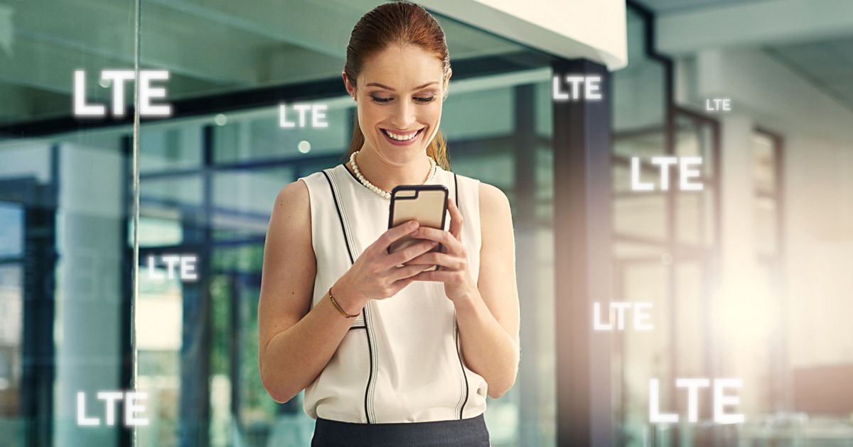 Geschäftsfrau schaut auf ihr Smartphone. Um sie herum mehrfach die Buchstaben „LTE“