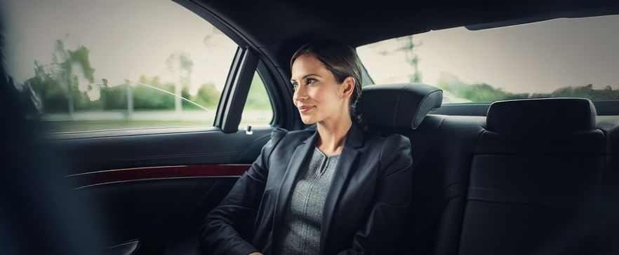 Frau im Anzug sitzt im Auto und schaut raus